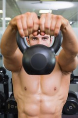 Fototapeta na wymiar Muscular man lifting kettle bell in gym