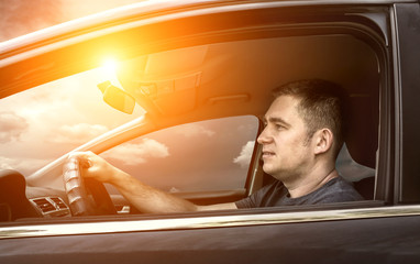 Man sitting and driving in the car under sunset sky