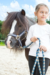Obraz premium beautiful little girl and a pony for a walk