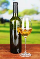 Wine bottle and glass of wine, on bright background