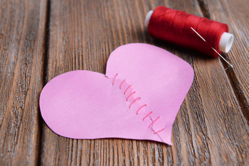 Broken heart and thread on wooden background