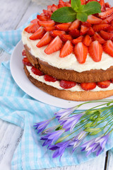 Delicious biscuit cake with strawberries on table close-up