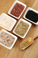 Variety of different sea salt in bowls on wooden table, close
