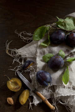 whole and slice prunes with leafs on rustic background