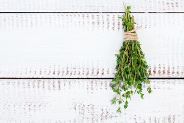 bunch of thyme on a white wooden background