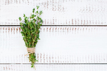 bunch of thyme on a white wooden background