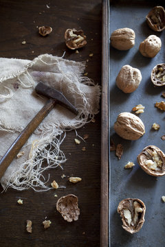 craked walnuts and hammer on rustic background