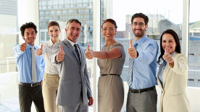 Business team showing thumbs up to camera