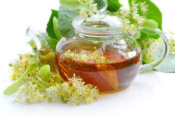 Teapot with linden tea and flowers on white background