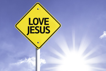 Naklejka premium Love Jesus road sign with sun background