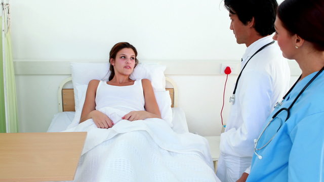 Doctor and nurse checking up on sick patient in bed