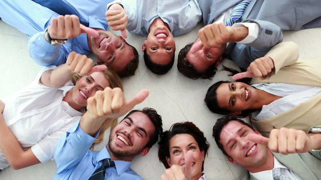 Business people lying in a circle showing thumbs up