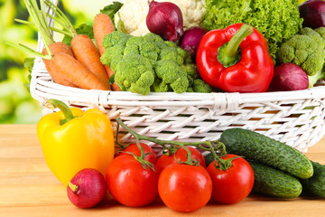 Fresh vegetables in white wicker basket on bright background