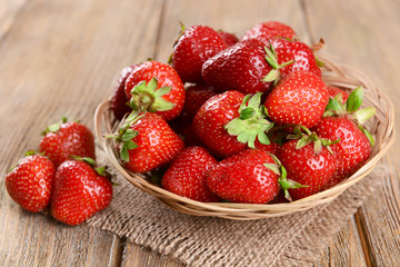 Ripe sweet strawberries in wicker basket on table close-up
