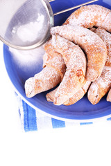 Tasty bagels with sugar powder on plate, isolated on white
