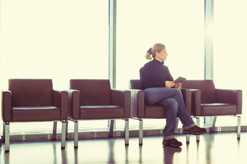 Woman using digital tablet at an airport, office, backlight.