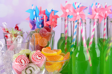 Bottles with drink and sweets on bright background