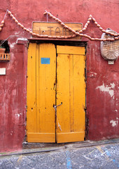 Una porta gialla di una casa rossa a Procida