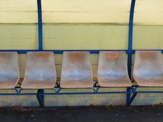 Old plastic seats on outdoor stadium players bench, worn chairs