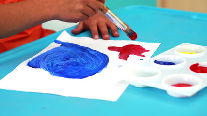 Cute little boy painting at table in classroom