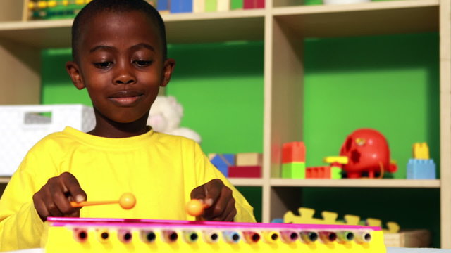 Cute little boy playing xylophone in classroom