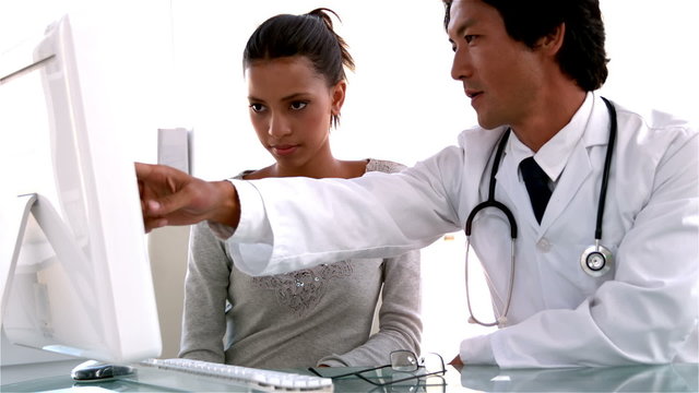 Doctor explaining something on computer to patient