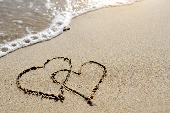 love concept - two hearts drawn on the beach sand