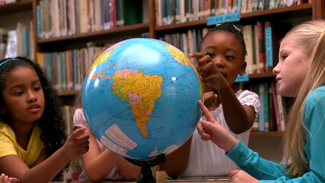 Cute little girls looking at globe in library