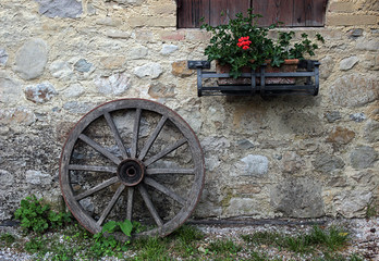 Obraz premium An old wooden wheel leaning against a stone wall