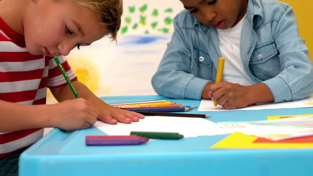 Cute little boys drawing at table in classroom