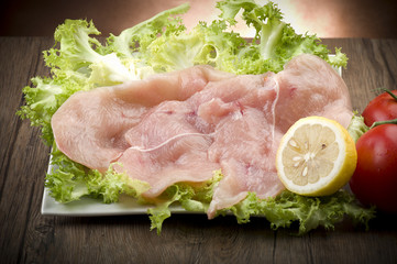 slices of chicken with salad on wood