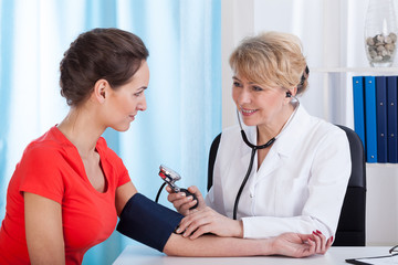 The doctor measures the pressure of woman
