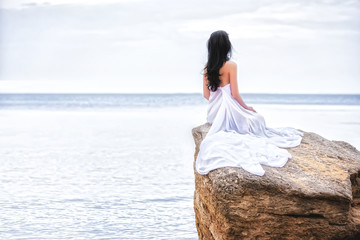 Attractive woman in white fabric on the rock