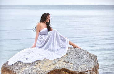 Attractive woman in white fabric on the rock