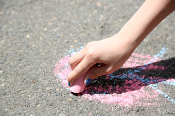 Girl drawing with chalk on asphalt
