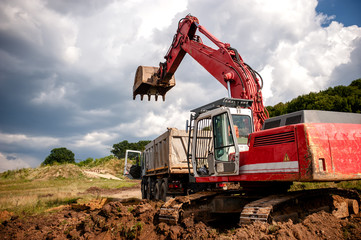 Heavy bulldozer and excavator loading and moving red sand