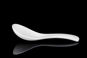 White empty ceramic spoon for soup on black background