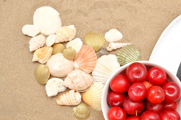 Plums, white hat and shells on wood and sand