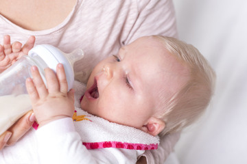 Baby 6 Monate greift nach dem Fläschchen