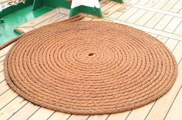 Fototapeta na wymiar Thick rope wrapped in spiral lying on deck of ship
