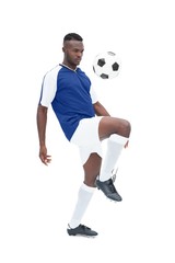Fototapeta na wymiar Football player in blue jersey controlling ball