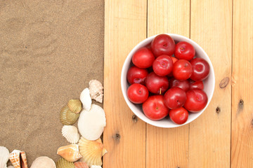Plums and shells on wood and sand