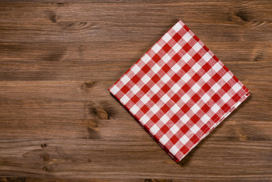 Folded red-white napkin on wooden table