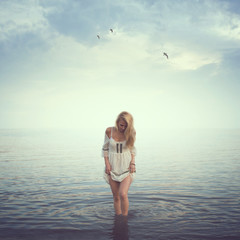 Fototapeta na wymiar Beautiful girl in the water. Beach, sunrise, cold morning.