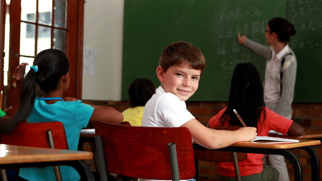 Little boy turning to smile at camera during class