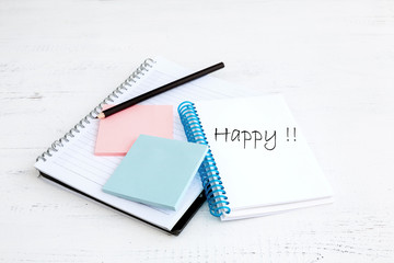 Notebook with pencil  and word happy
