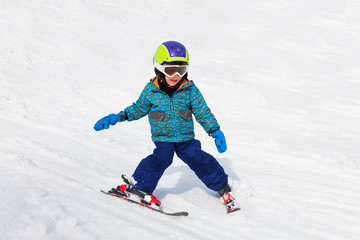 Fototapeta na wymiar Smiling boy in ski mask learns skiing
