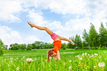 Little girl doing gymnastics on grass