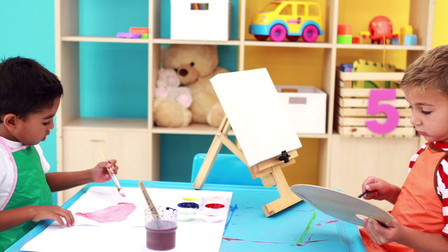 Cute little boys painting at table in classroom