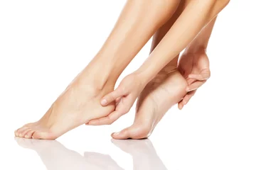 Foto op Plexiglas Pedicure vrouw die haar voeten teder aanraakt